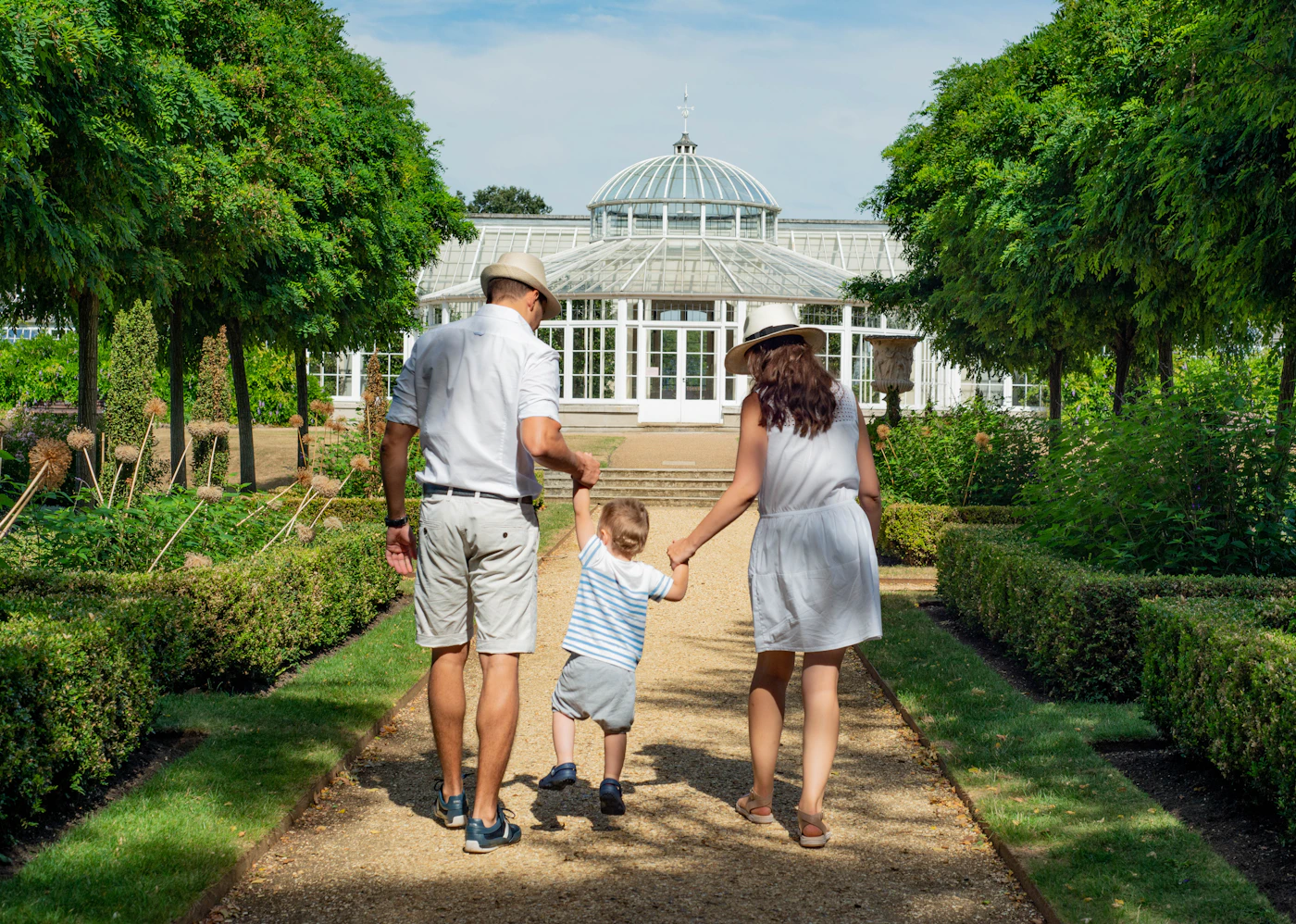 Família caminhando de mãos dadas em um jardim.