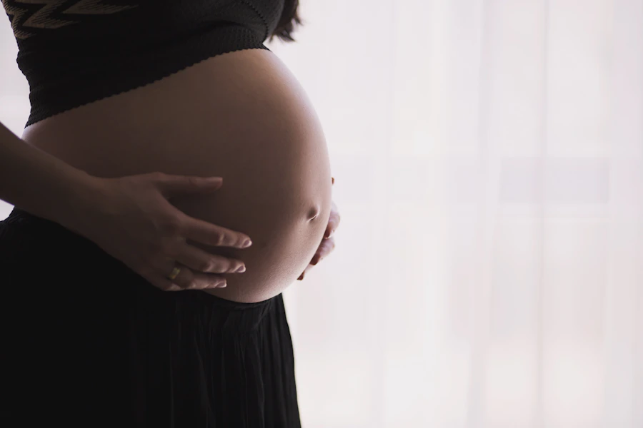 Gestante com as mãos apoiadas na barriga.